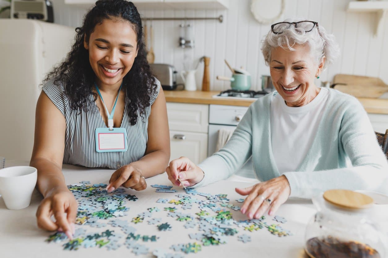 Alltagsbegleiterin und Seniorin beim gemeinsamen Puzzeln